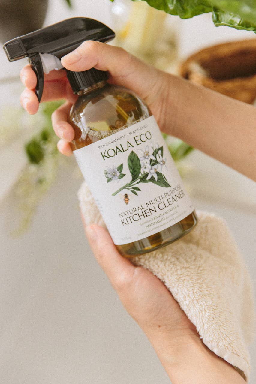 Natural Multi-Purpose Kitchen Cleaner in hand, eco-friendly spray bottle with lemon myrtle and mandarin design.