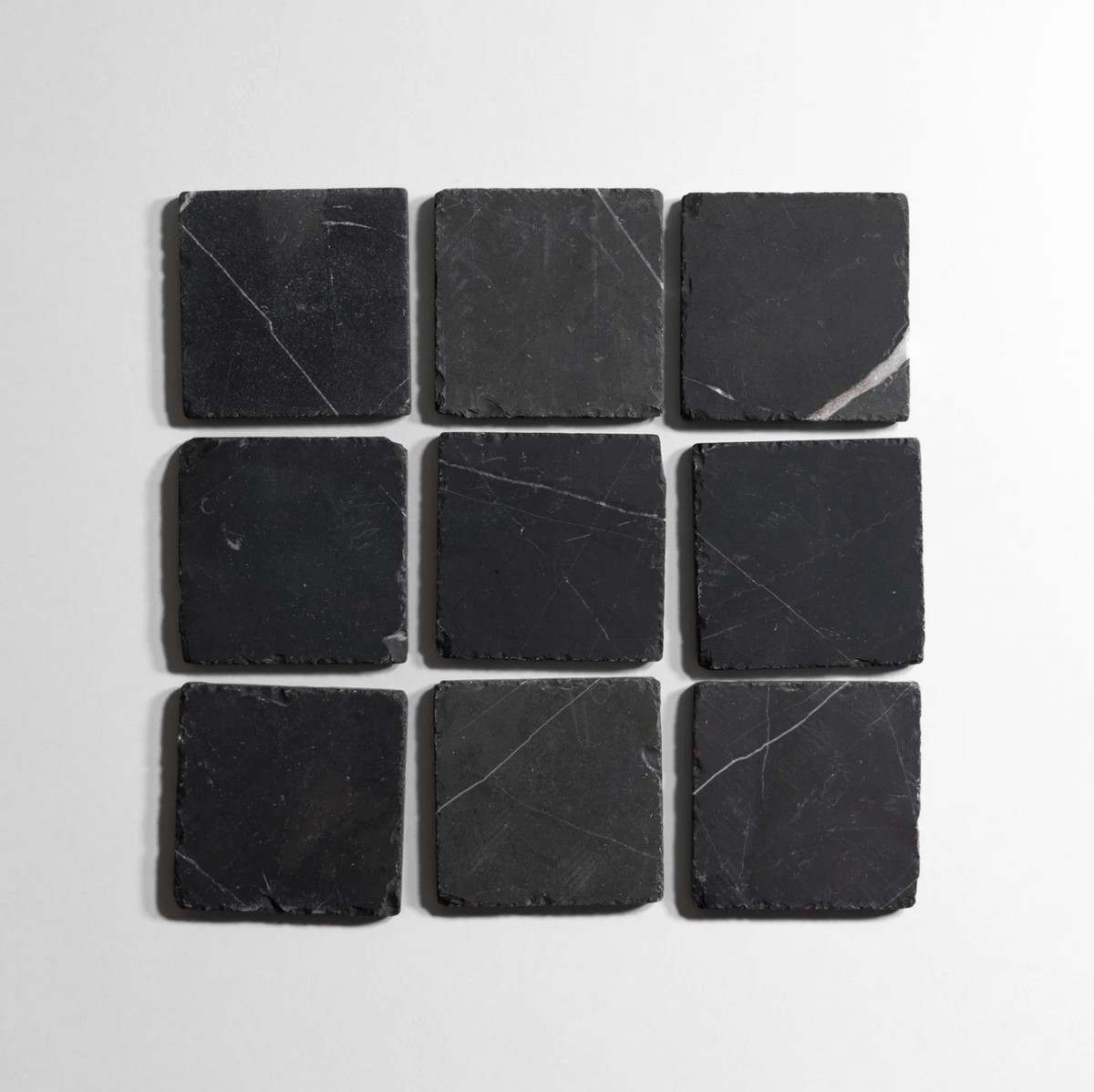 Nero St. Gabriel 6-inch tumbled stone tiles arranged in a grid, showcasing a sleek black finish.